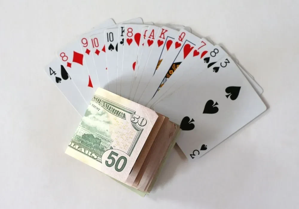 A pile of money laid on top of playing cards