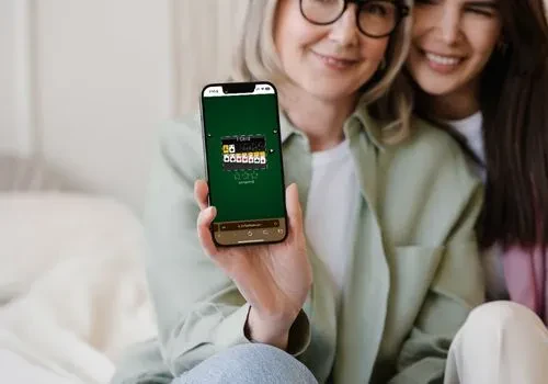 A senior citizen showing up her phone screen which shows an on-going game in 247 Solitaire