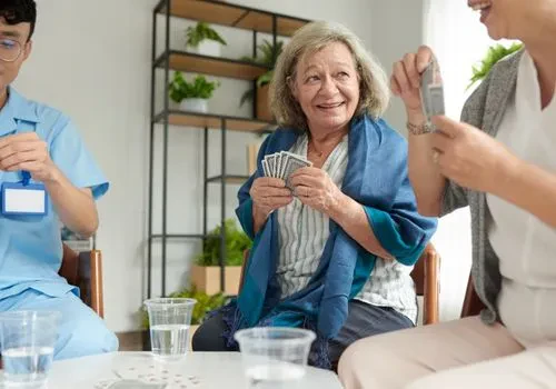 A female memory care patient smiling at her caregiver as they play some card games