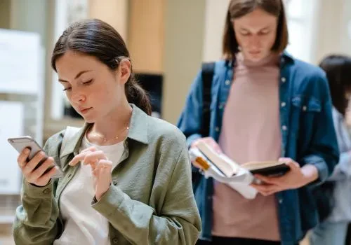 A woman in line excitedly playing a game on their phone