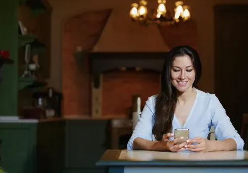 A woman smiling while using her phone to play games